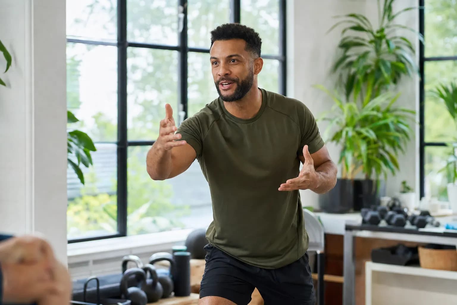 Personal Trainerin und Klient bei Übung in hellem modernem Trainingsraum mit grossen Fenstern.